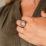 bague epaisse ovale berenice argentee avec grand anneau portee sur le majeur gauche main posee sur la poitrine
