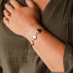 bracelet coquillage pour femme en acier dore et texture porte poignet gauche main posee poitrine margaux