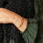 bracelet maillon acier dore avec trois mailles ovales lisses au milieu et porte poignet gauche philippine