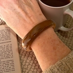 Bracelet en résine marron Olga porté au poignet, montrant sa forme organique et sa teinte marron