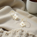 mini creoles avec pendentif zara anneau dore et fleur blanche nacree exposees sur tissu beige