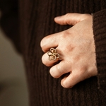 bague fleur ajourée dorée acier inoxydable portée sur main fond marron