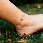 chaine de cheville coquillage dorée portée sur jambe droite lou