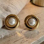 Boucles d’oreilles vintage Paulette dorées avec boule en résine nacrée sur table en bois