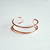 bracelet manchette femme minimaliste ouvert et plaque or rose expose fond blanc violaine