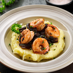 Crevettes sautées à lail noir sur un écrasé de pomme de terre à lhuie dolive à lail noir