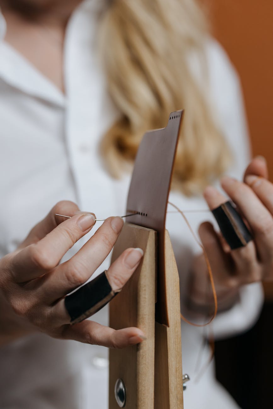 Mains faisant une couture sellier