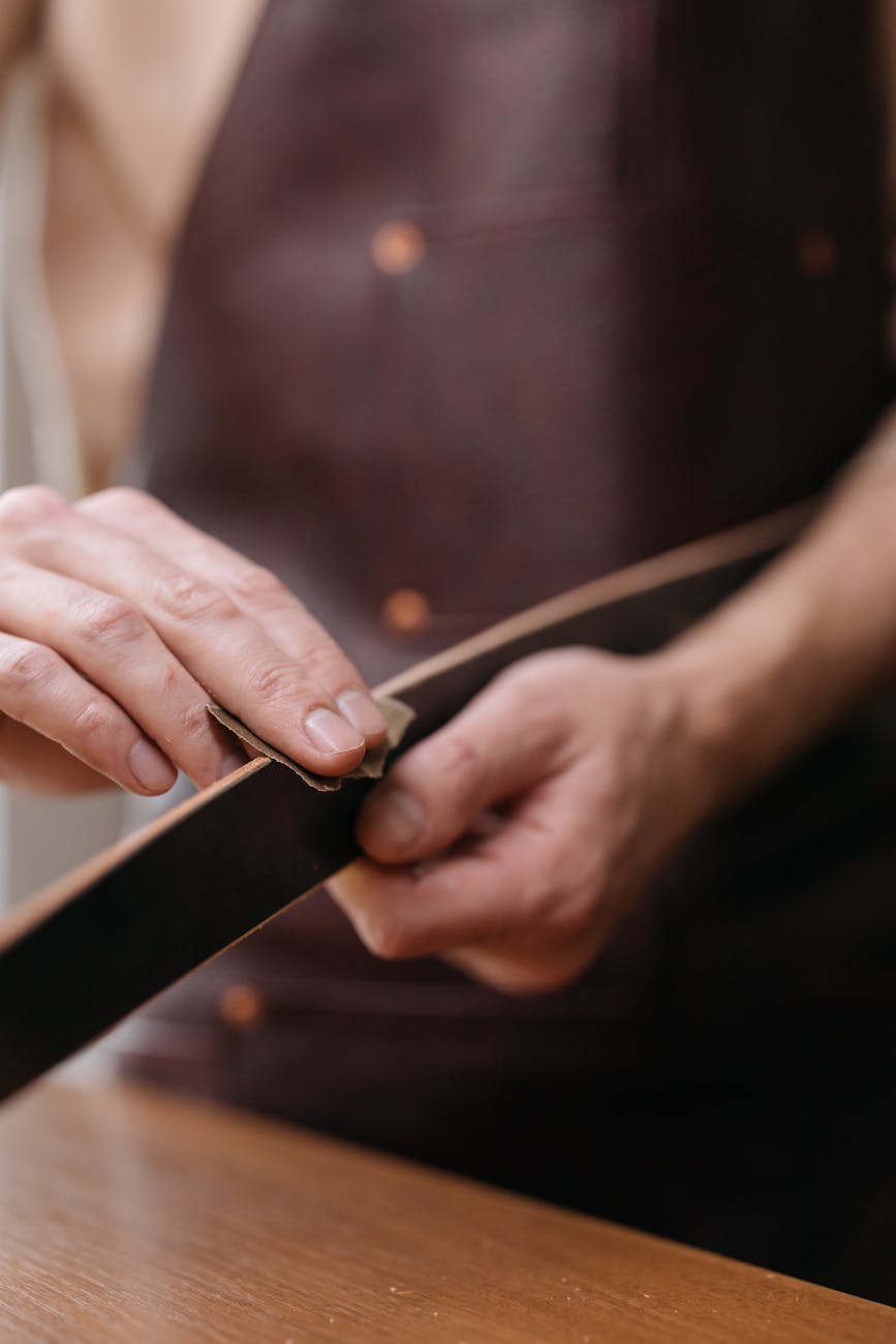 Mains d'artisan astiquant la tranche d'un cuir