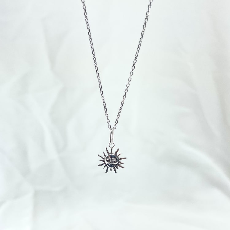 Collier louis : Collier composé dune chaine fine et dun pendentif en forme de soleil gravé dun petit visage en son centre. En argent 925