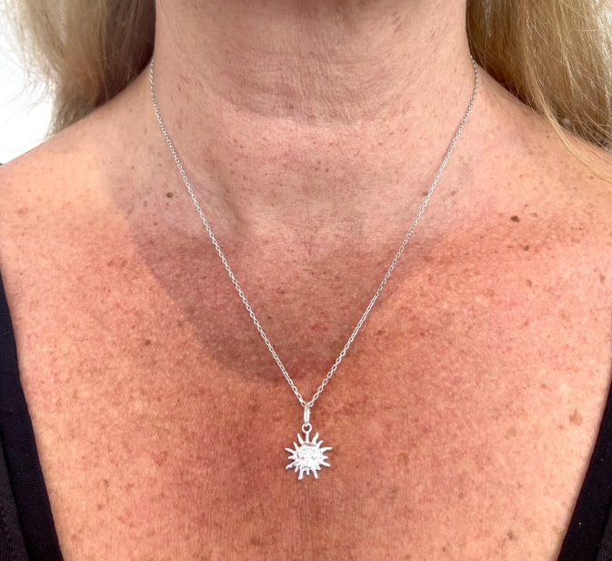 Collier Louis: Collier composé dune chaine fine et dun pendentif en forme de soleil gravé dun petit visage en son centre. En argent 925