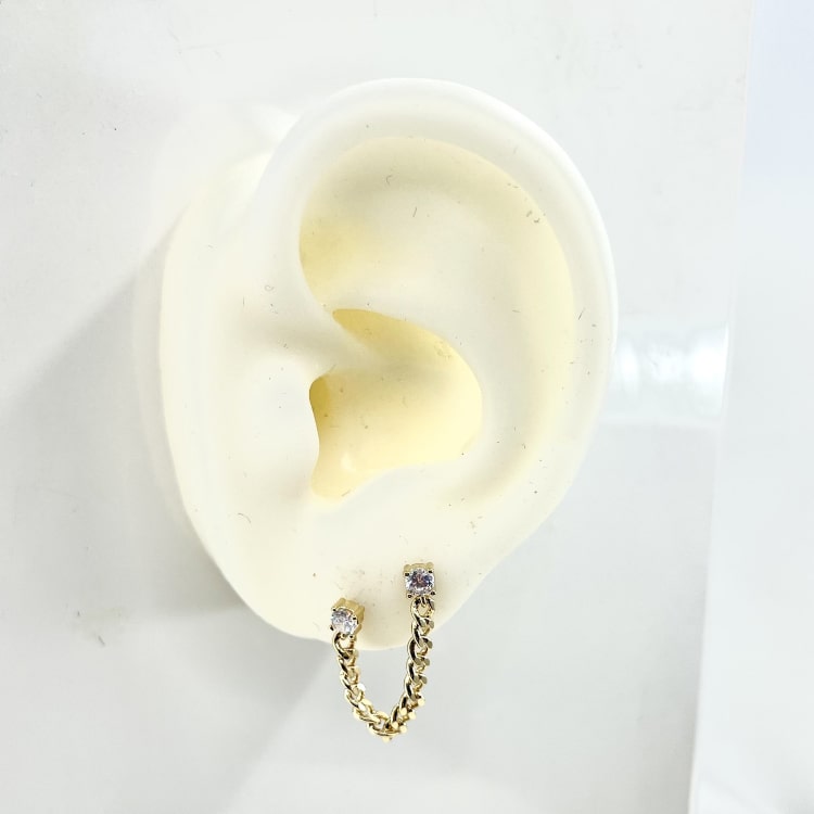 Ambroise: Boucle doreille composée de 2 oxydes de zirconium serties par 4 griffes et reliés entre eux par une jolie chaine gourmette. En plaqué or 3 microns. Vendue à lunité