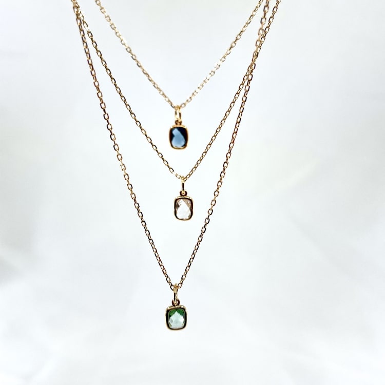 Collier  Nelson : Collier composé dune chaine fine et dun pendentif rectangulaire serti dun oxyde de zirconium teinté bleu, vert deau ou blanc transparent. En plaqué or 3 microns