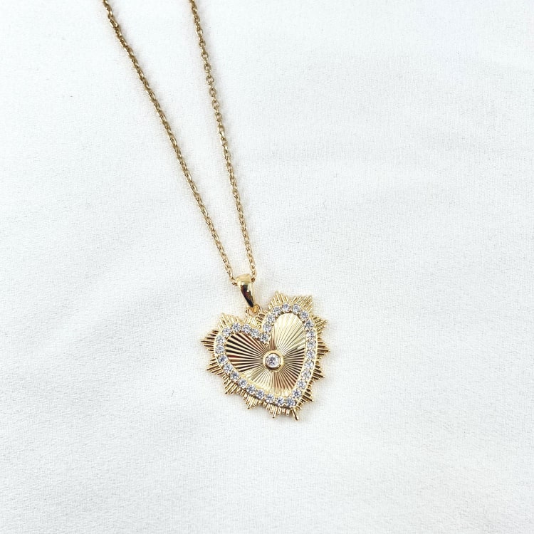 Collier Apollo: collier composé dune chaine fine et dun pendentif coeur en zirconiums blancs entouré dun joli soleil strié. En plaqué or 3 microns