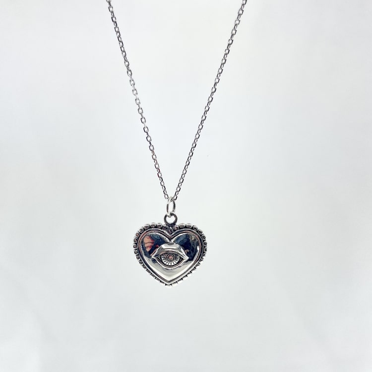 Nathan: collier composé dune chaine fine et dun pendentif coeur doté dun petit oeil en relief en son centre. En argent 925
