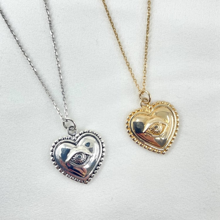 Nathan: collier composé dune chaine fine et dun pendentif coeur doté dun petit oeil en relief en son centre. En plaqué or 3 microns et en argent 925