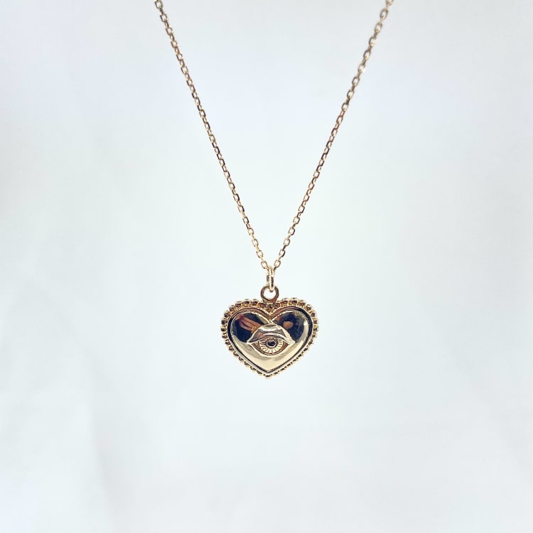 Nathan: collier composé dune chaine fine et dun pendentif coeur doté dun petit oeil en relief en son centre. En plaqué or 3 microns