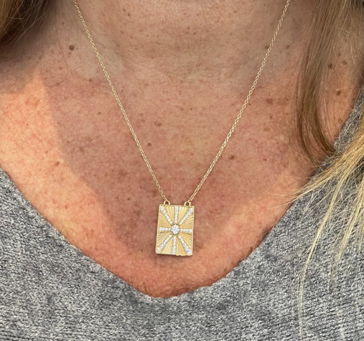 Collier Steeve: Collier composé dune chaine fine et dun pendentif rectangulaire strié incrusté de zirconiums blancs formant un soleil. En plaqué or 3 microns.