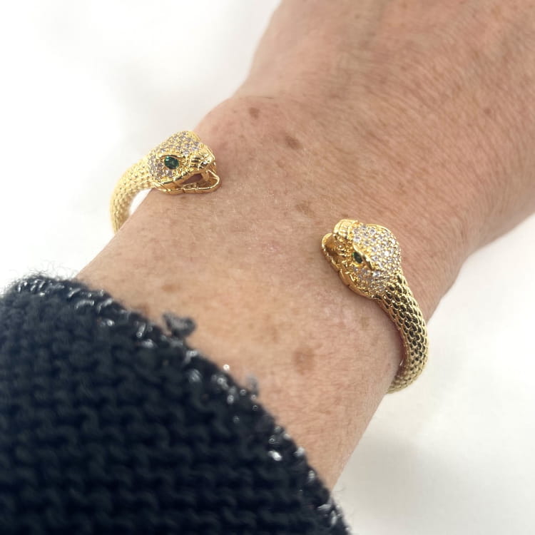Jonc Dan: Jonc ouvert et écaillé doté de deux têtes de serpent sertis de zirconiums blancs et de zirconiums verts au niveau des yeux. En plaqué or  18 carats