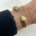 Jonc Leo: Jonc ouvert orné de deux têtes de lion sertis de zironiums blancs et de zirconiums verts au niveau des yeux. En plaqué or 18 carats
