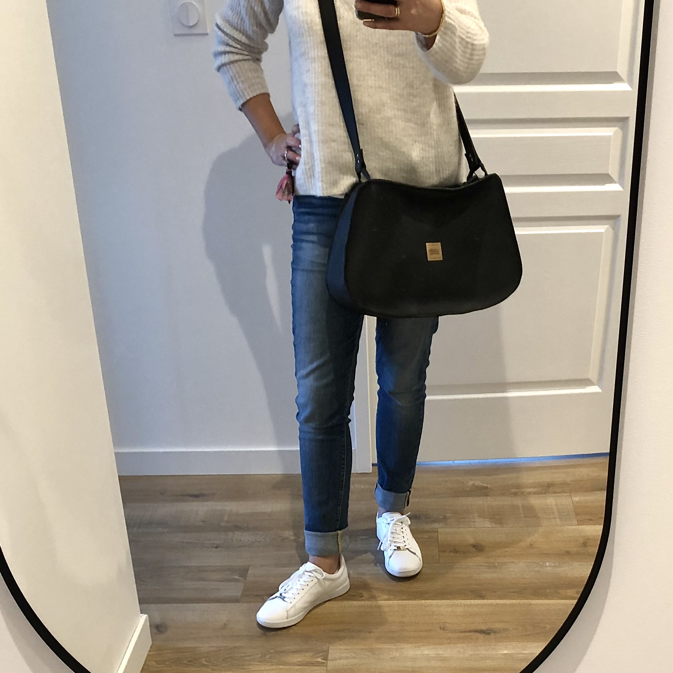 large sac noir en cuir porté en bandoulière croisé par une femme de face