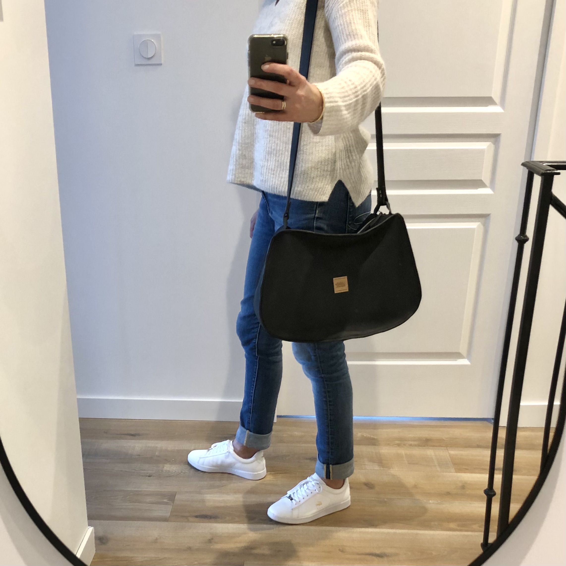 grand sac à main en cuir noir porté épaule par une femme de profil