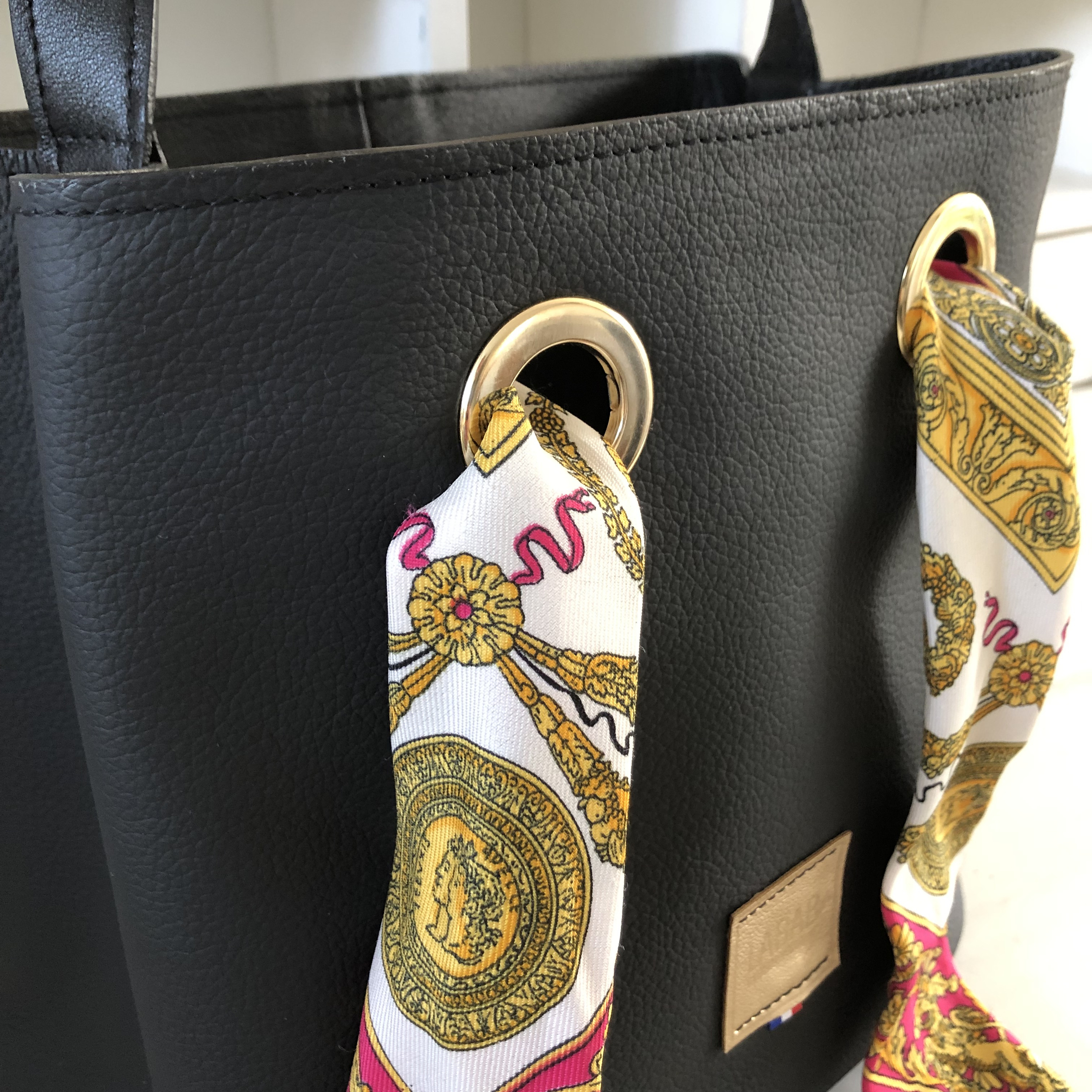 zoom sur devant sac cuir noir œillets dorés et lien en foulard souvenir