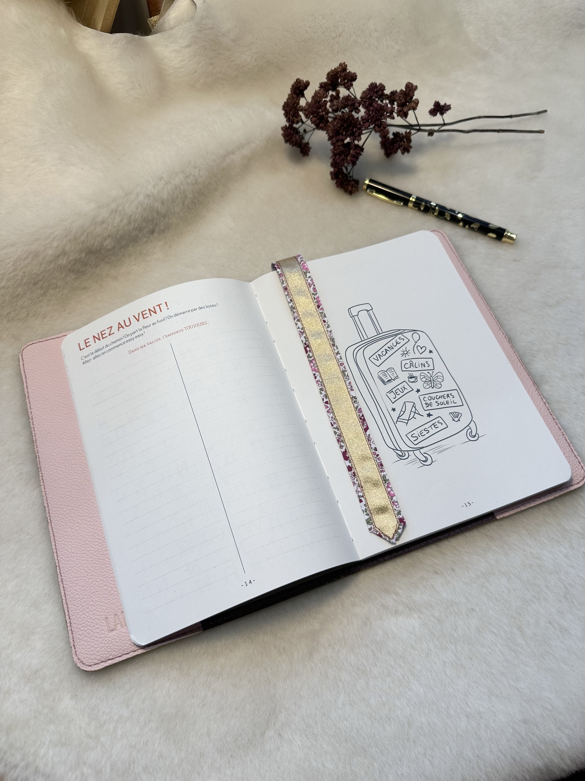 Carnet décriture dans le protège-carnet en cuir ouverts avec le marque-page fleuri et doré au milieu