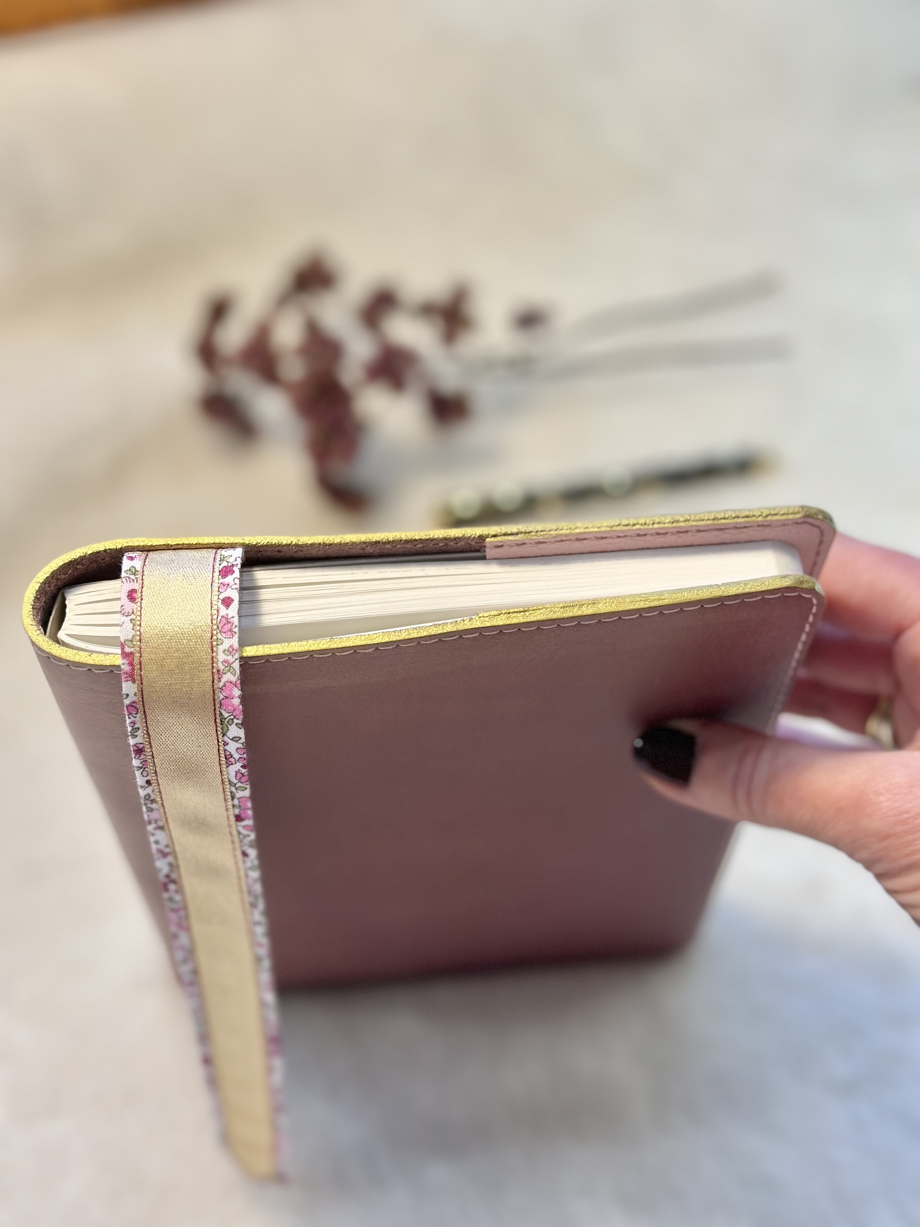 vue des tranches dorées du protège-carnet en cuir parme et du marque-page en tissu liberty