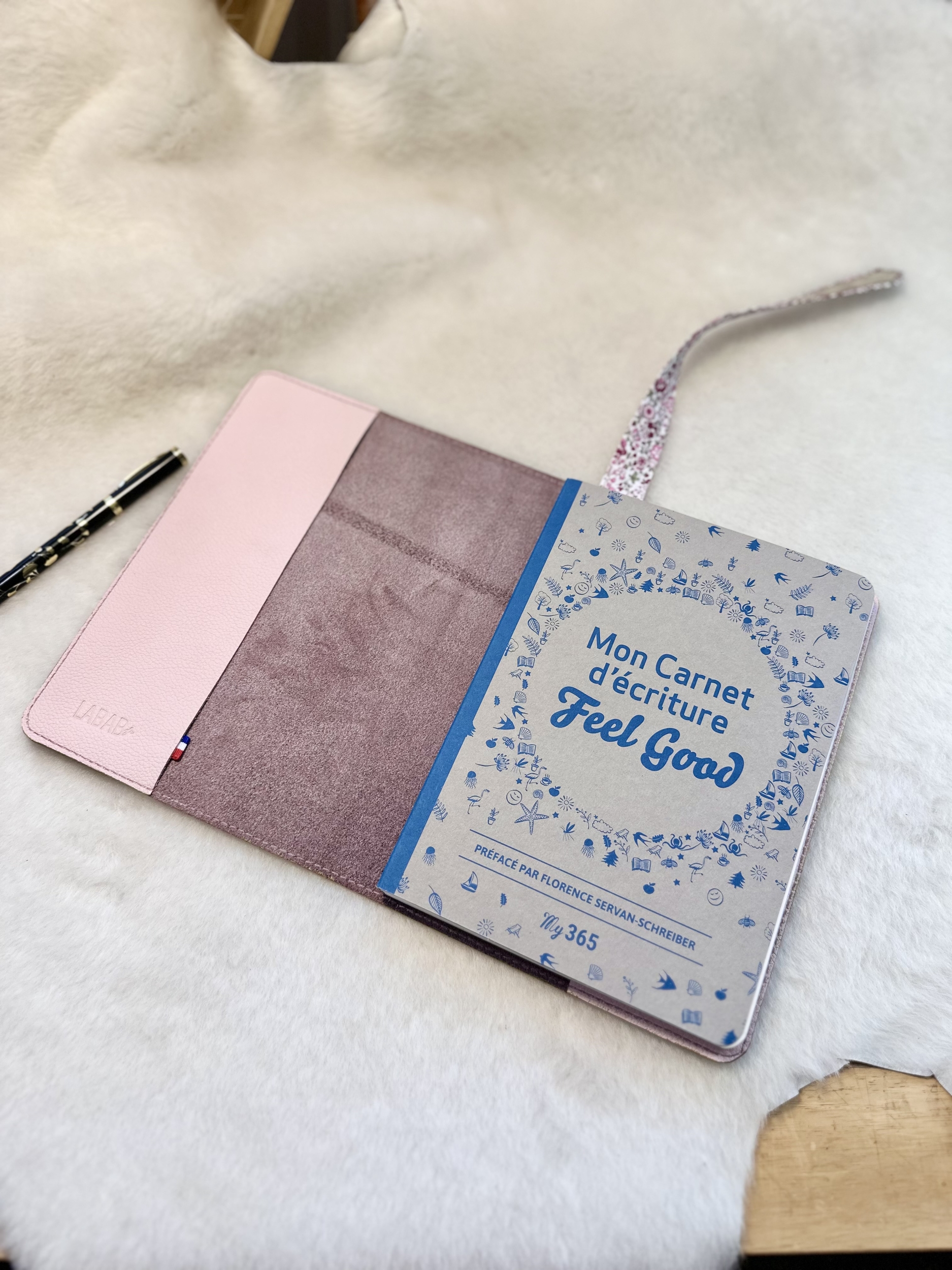 Cahier fourni: "Mon carnet carnet Feel Good" préfacé par Florence Servan Schreiber posé sur le protège-carnet en cuir ouvert
