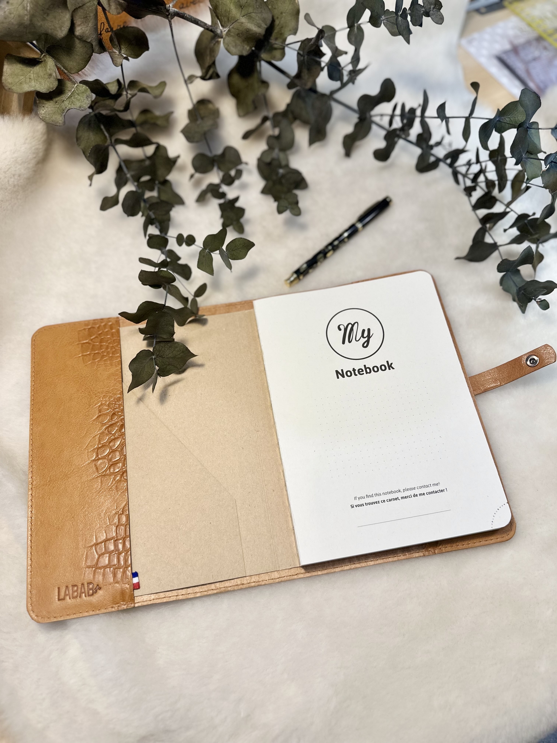 Protège-carnet ouvert avec le note book fourni, vue du rabat en cuir avec ruban tricolore et logo LABAB marqué à chaud