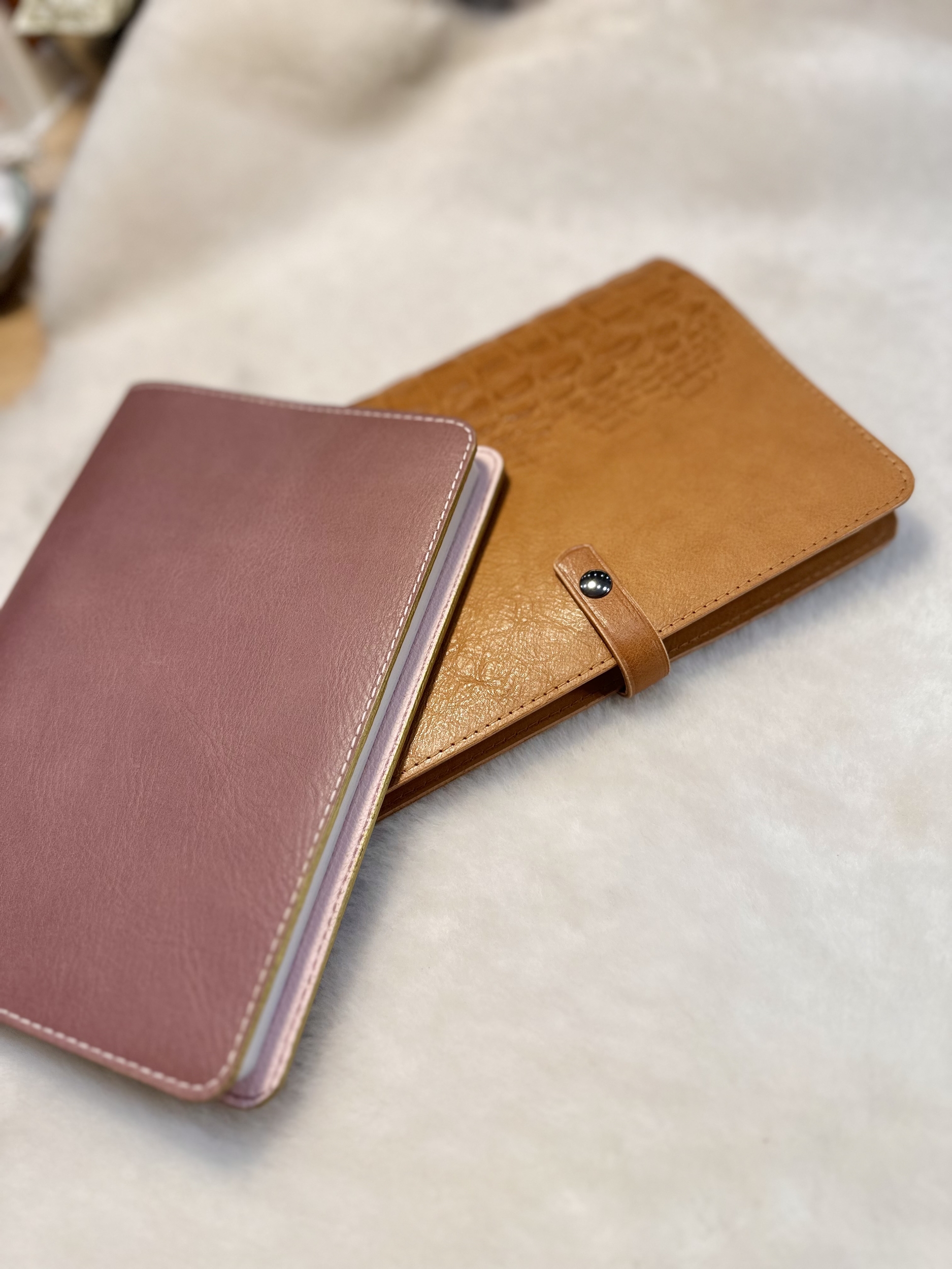 Protège-carnet en cuir parme LABAB avec carnet dedans posé sur protège-carnet en cuir camel imitation crocodile avec carnet dedans également