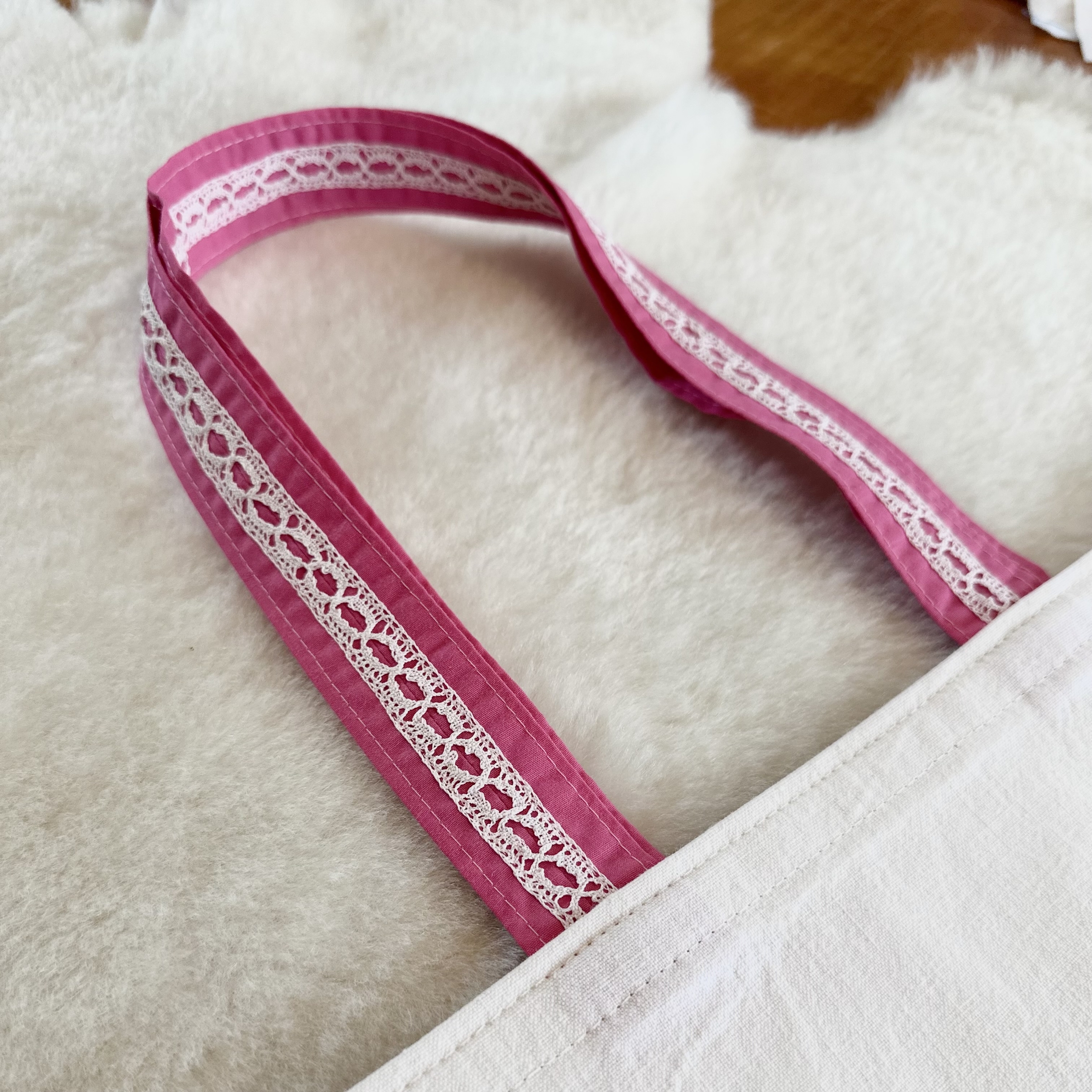 dentelle souvenir blanche cousues sur anses en tissu rose foncé