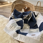 Patchwork douillet présenté dans un couffin tressé avec un nounours en peluche