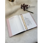 Carnet décriture dans le protège-carnet en cuir ouverts avec le marque-page fleuri et doré au milieu