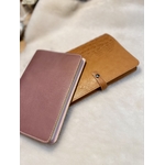 Protège-carnet en cuir parme LABAB avec carnet dedans posé sur protège-carnet en cuir camel imitation crocodile avec carnet dedans également