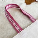 dentelle souvenir blanche cousues sur anses en tissu rose foncé