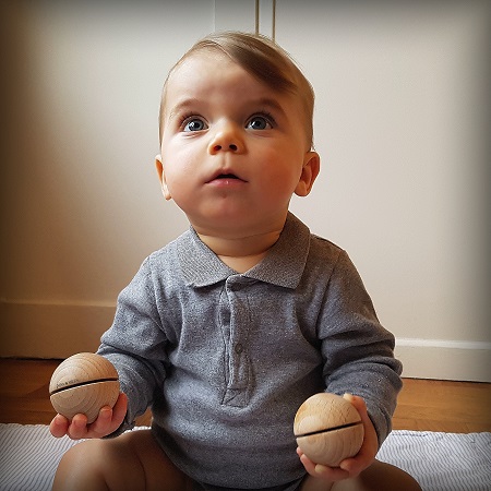 bébé assis avec 2 petites boules sonores