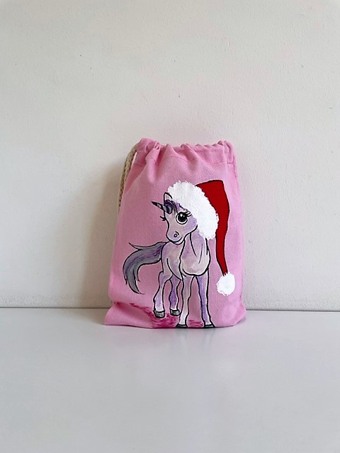 pochon rose en coton avec une licorne coiffée dun père Noël peinte à la main par Elles et No.
