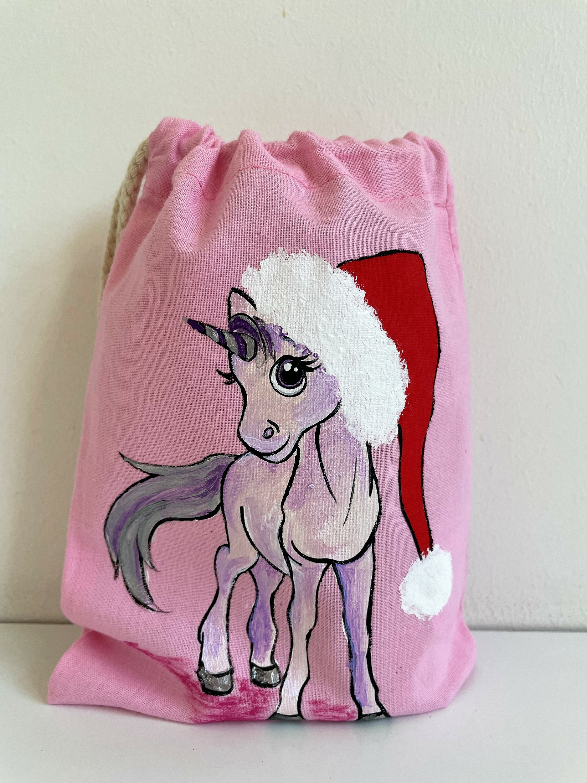 pochon rose en coton avec une licorne coiffée d'un père Noël peinte à la main par Elles et No.