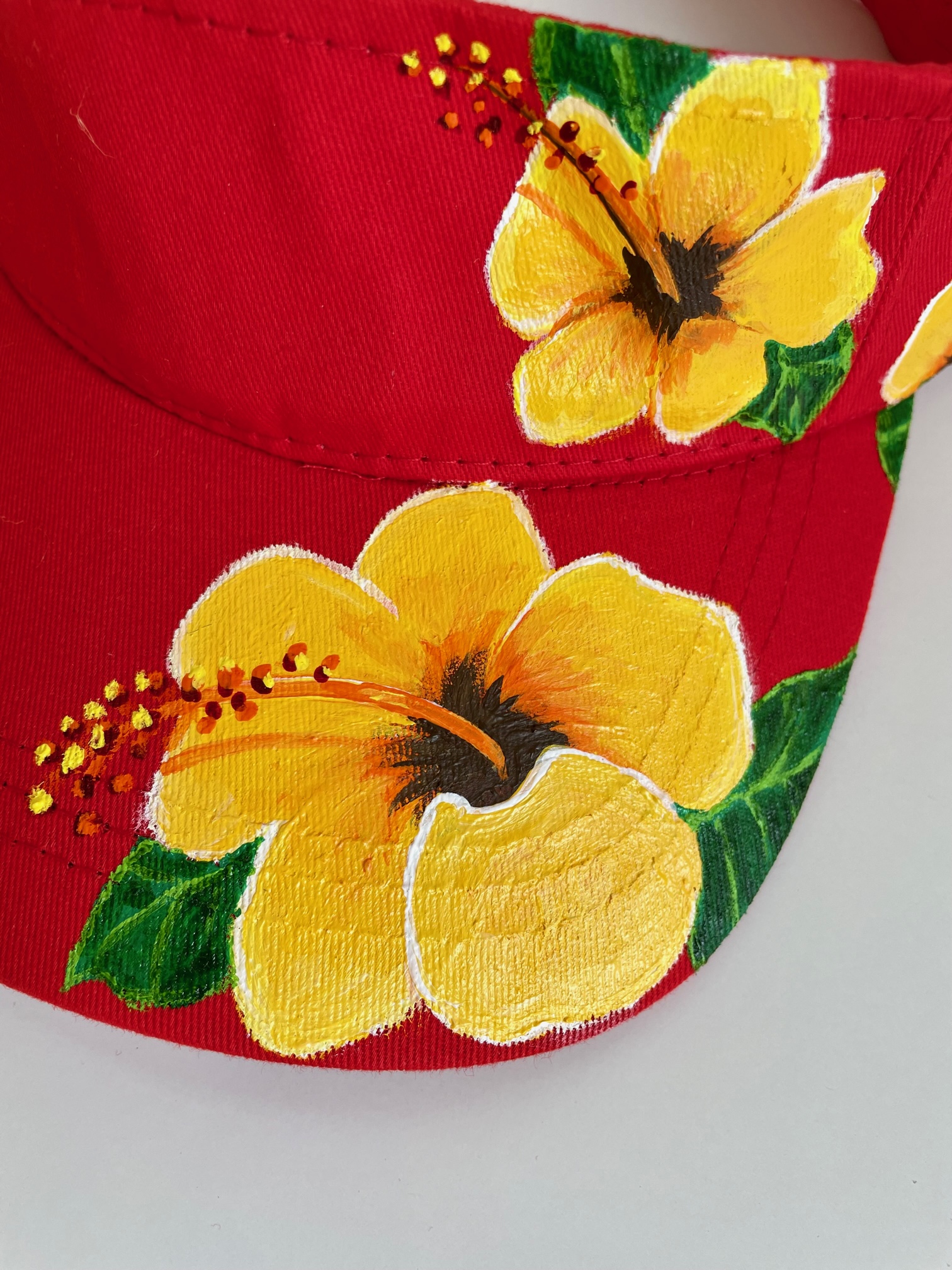Visière rouge avec des hibiscus jaune peinte à la main par Elles et No.