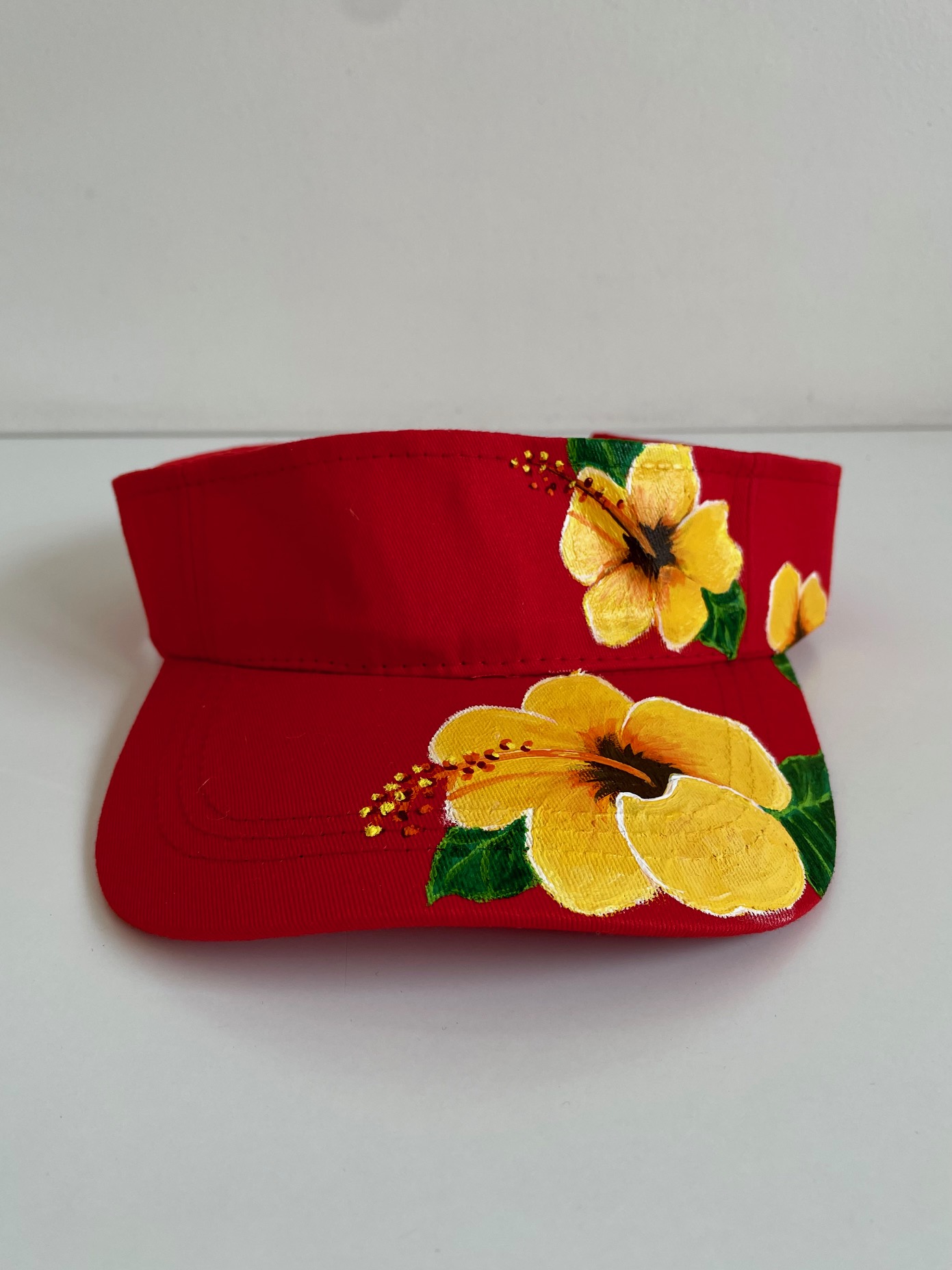 Visière rouge avec des hibiscus jaune peinte à la main par Elles et No.
