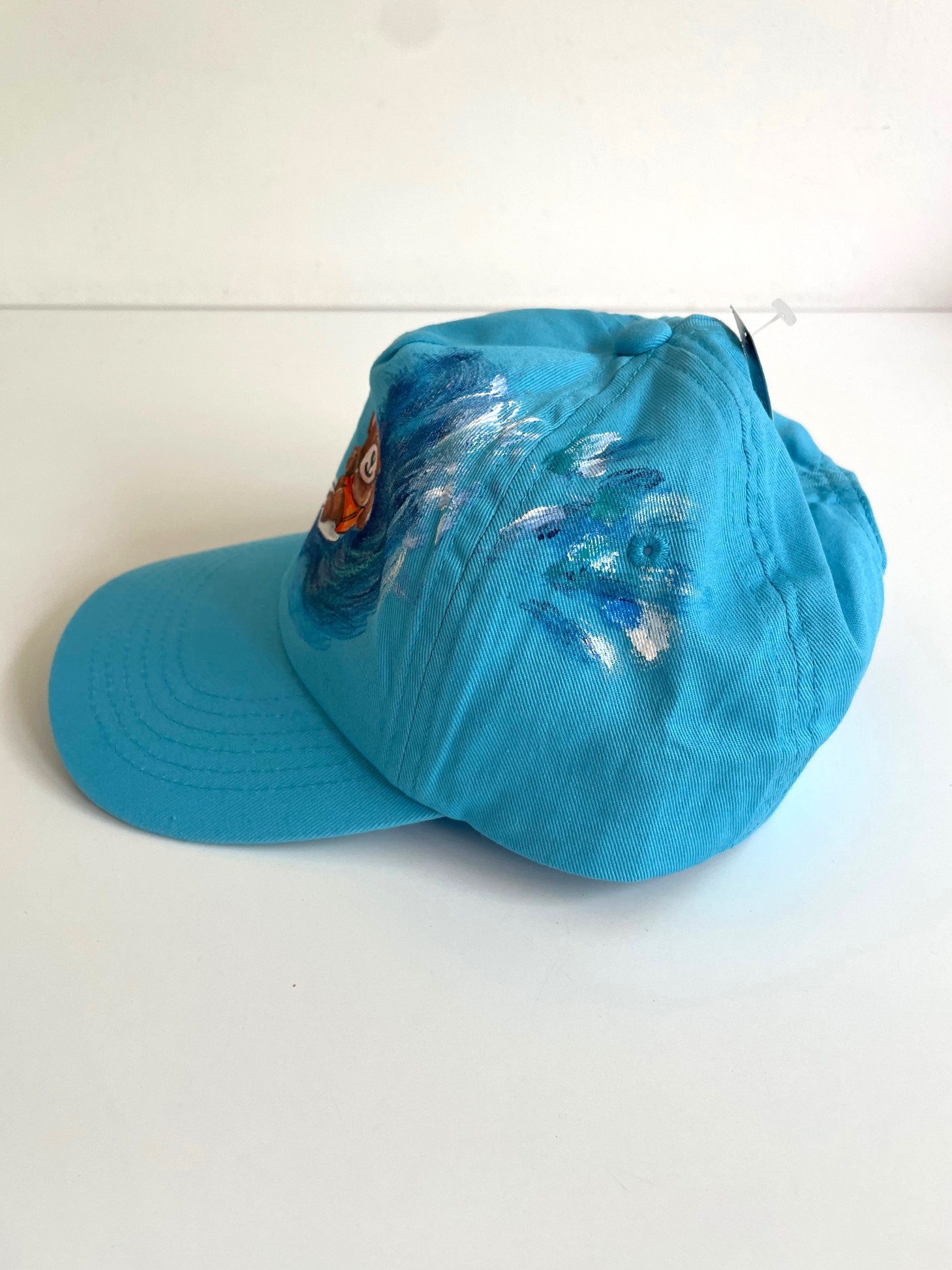 casquette enfant bleue avec un ourson surfeur peint à la main par Elles et No.