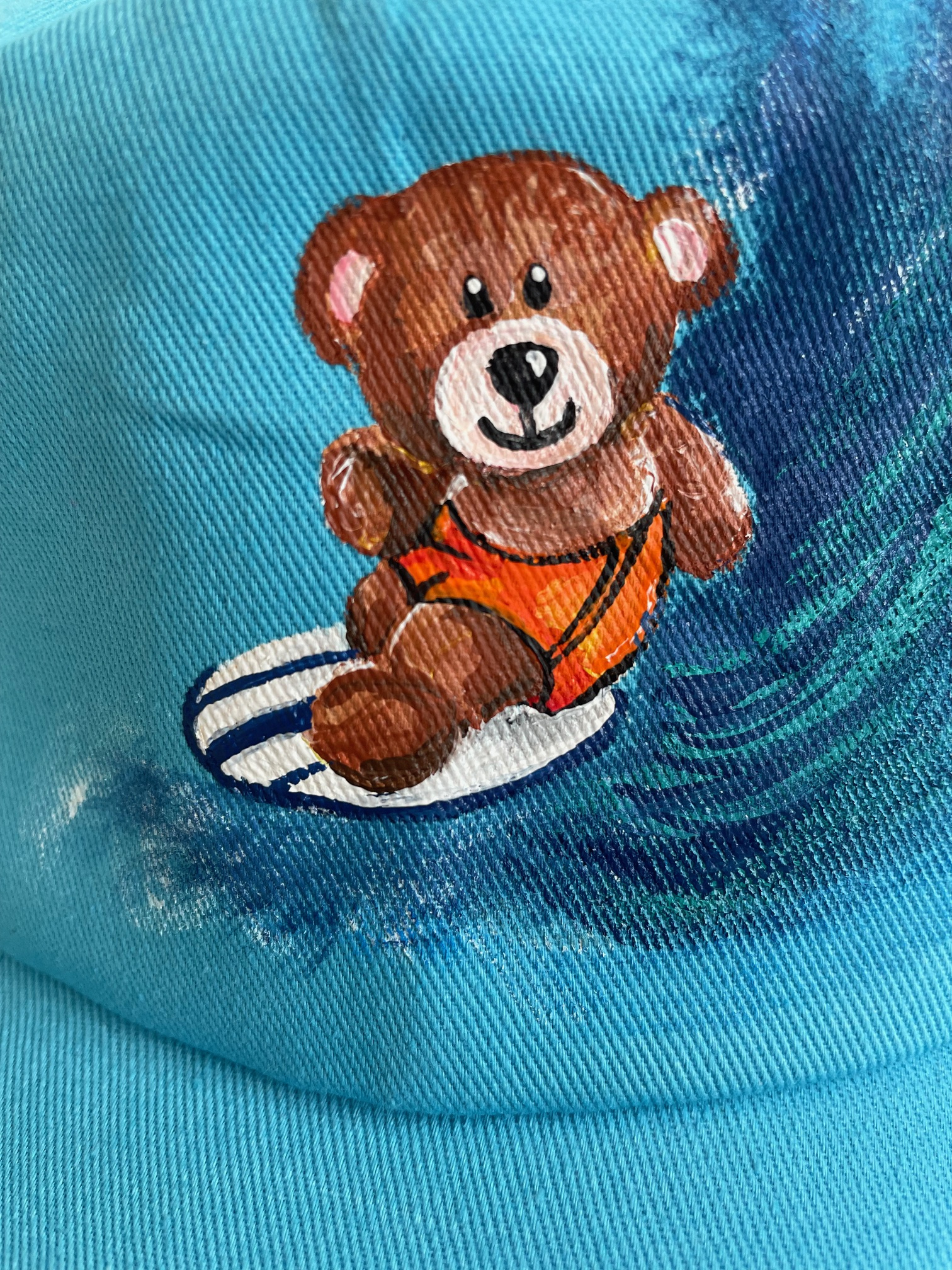 casquette enfant bleue avec un ourson surfeur peint à la main par Elles et No.