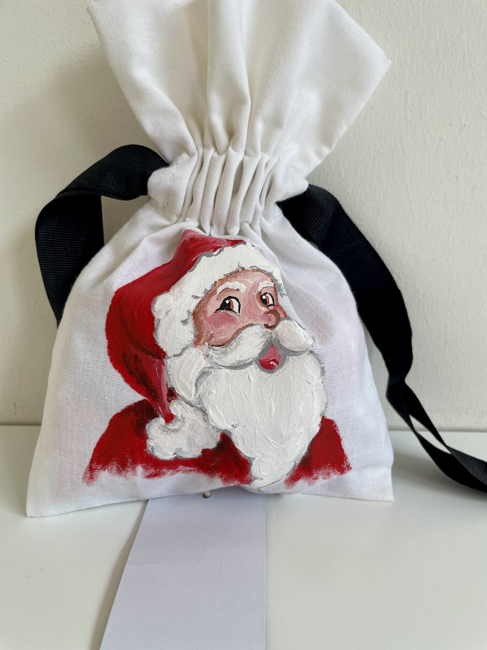Pochette coton blanc, ruban satin noir, avec tête de père Noël peinte à la main par Elles et No.