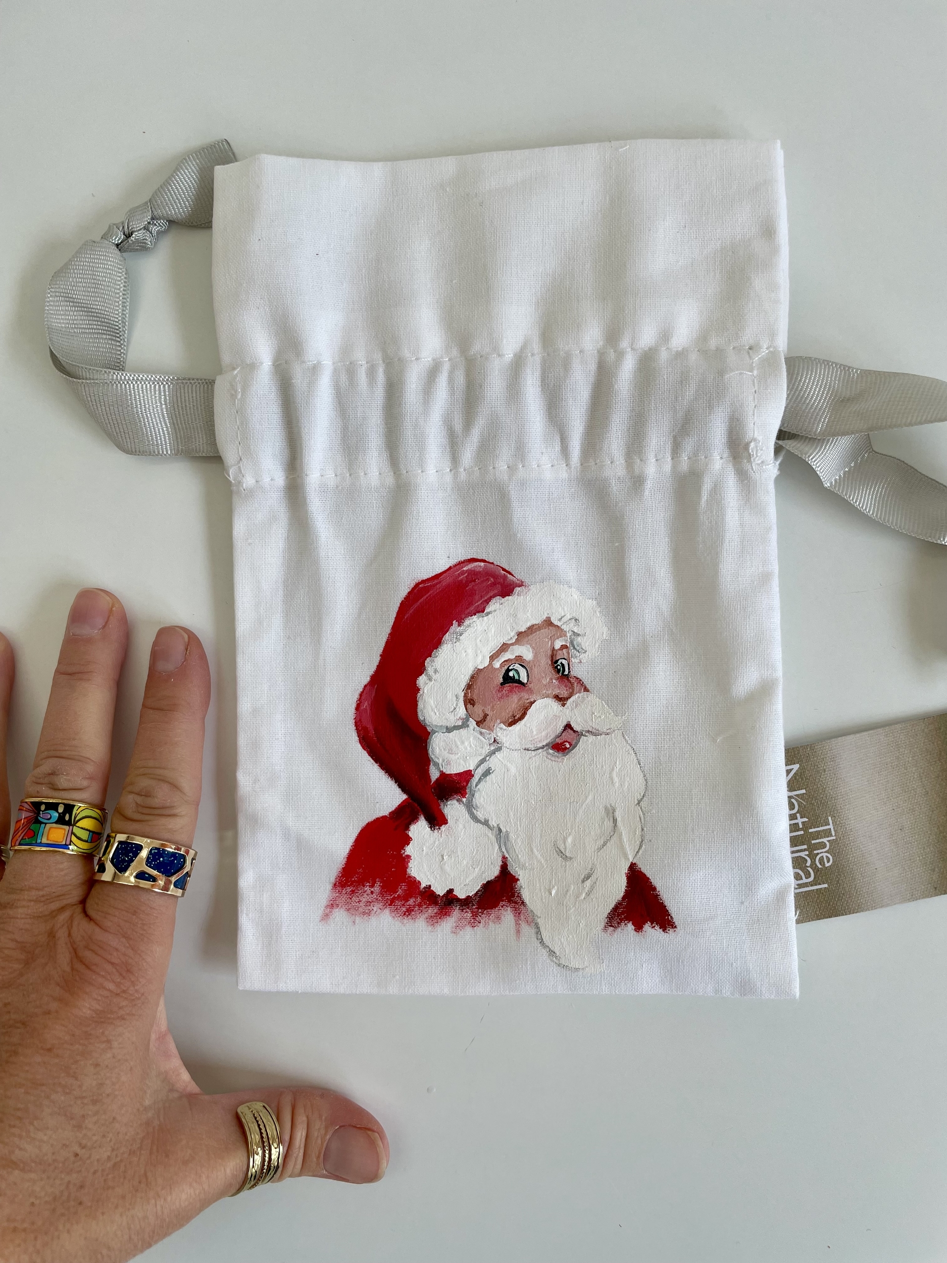Pochette coton blanc, ruban satin gris, avec tête de père Noël peinte à la main par Elles et No.