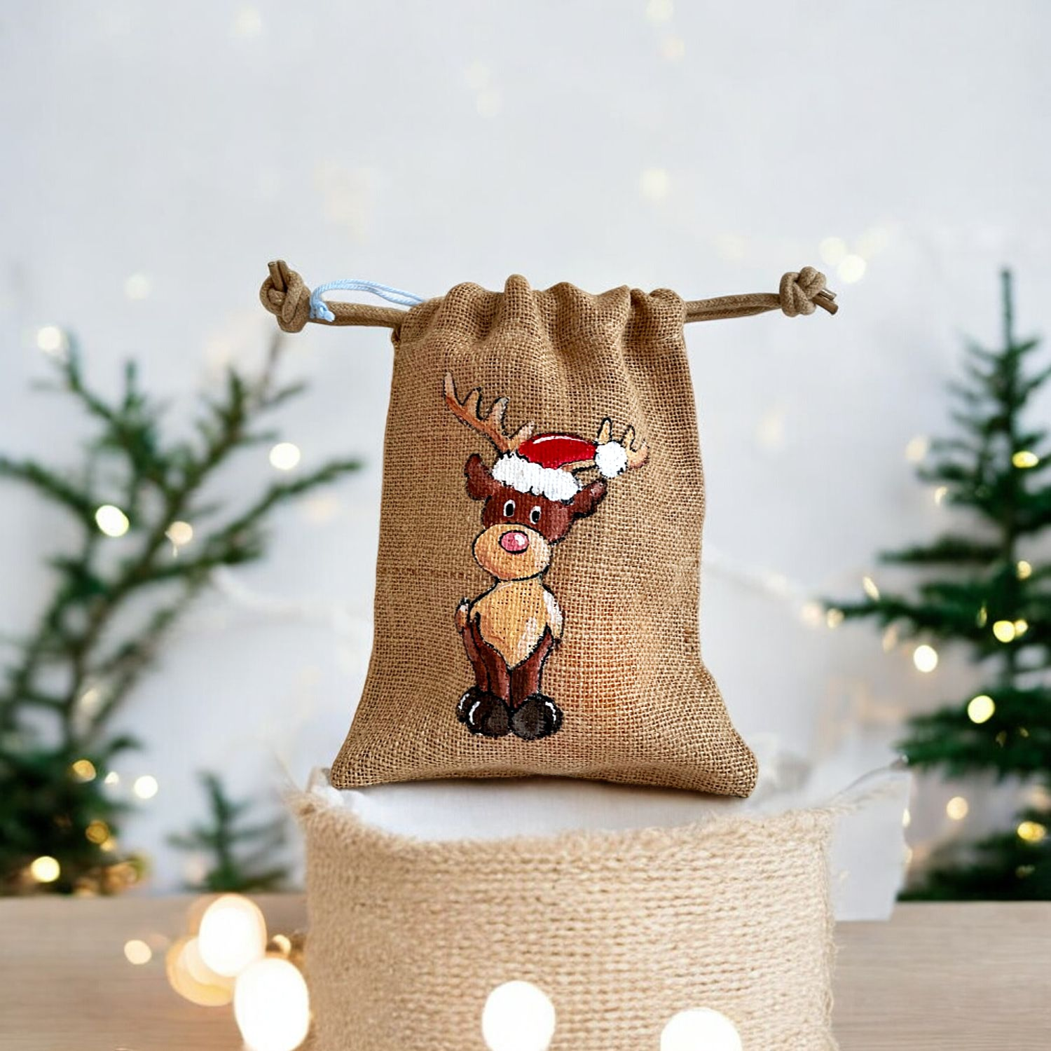 Pochon en jute avec un renne coiffé dun bonnet de père Noël peint à la main par Elles et No.