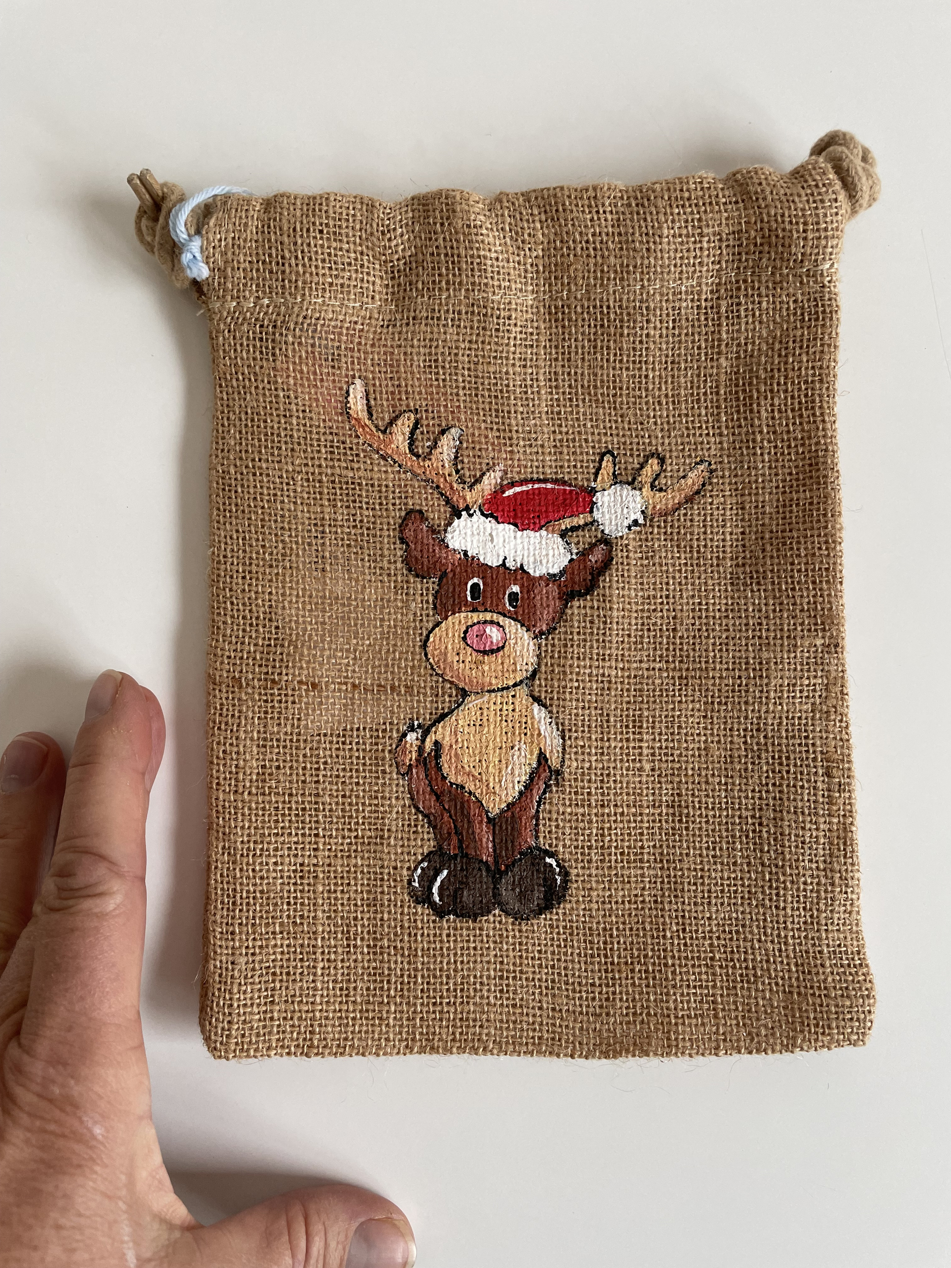 Pochon en jute avec un renne coiffé dun bonnet de père Noël peint à la main par Elles et No.