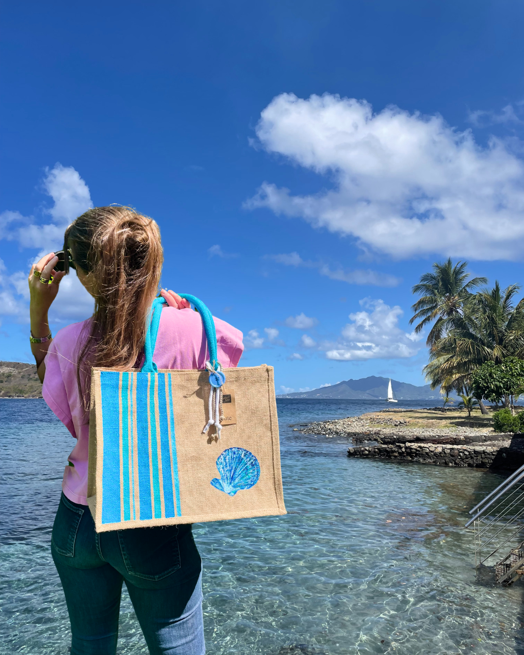 Collection Capsule Bayadère sac de plage avec des rayures bleues style Bayadère et un coquillage peints à la main par Elles et No. Présenté porté à la plage