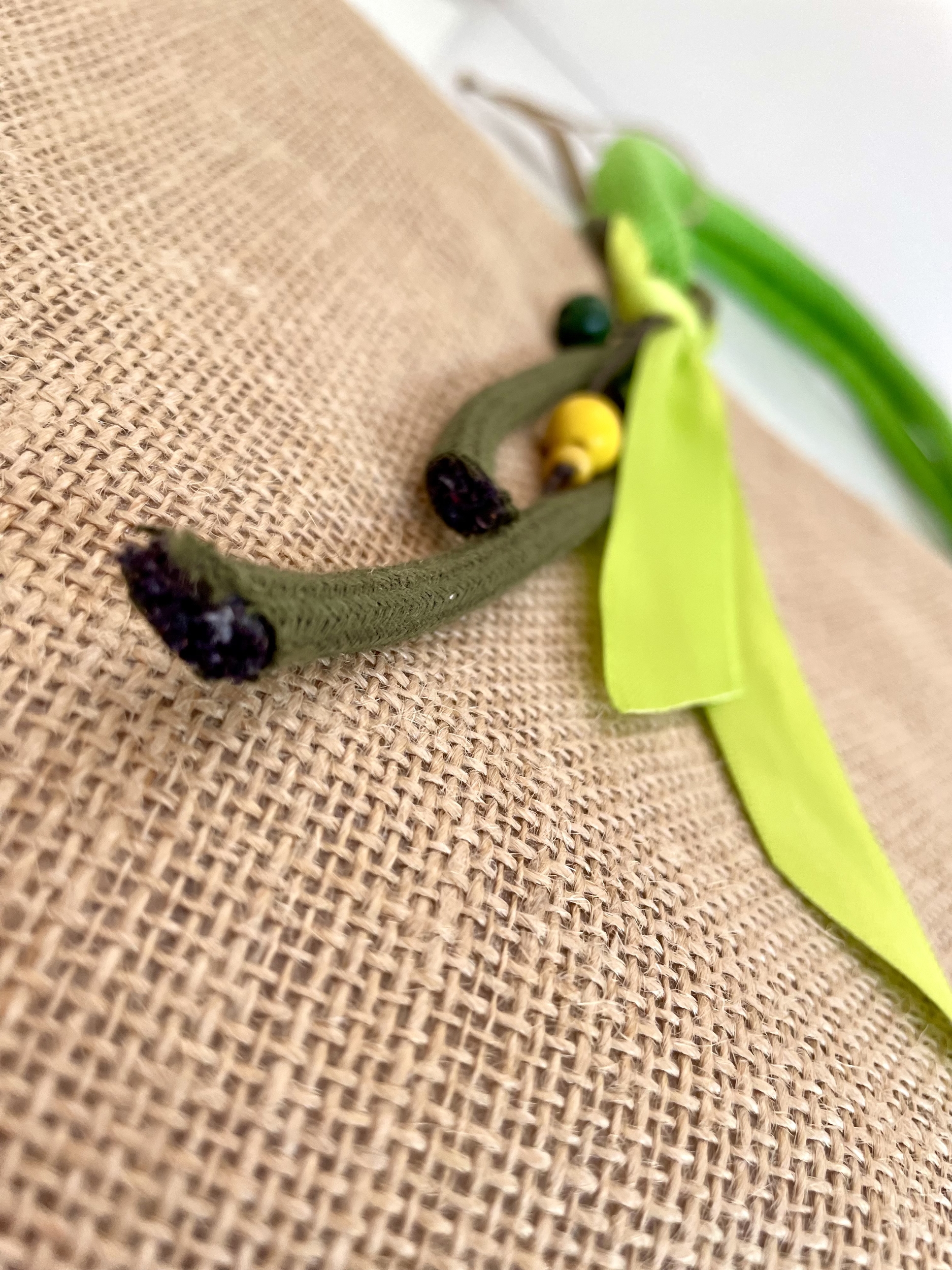 sac de plage en jute à anses vertes avec un hippocampe dans les tons jaune et vert peint à la main par Elles et No., détail du colifichet