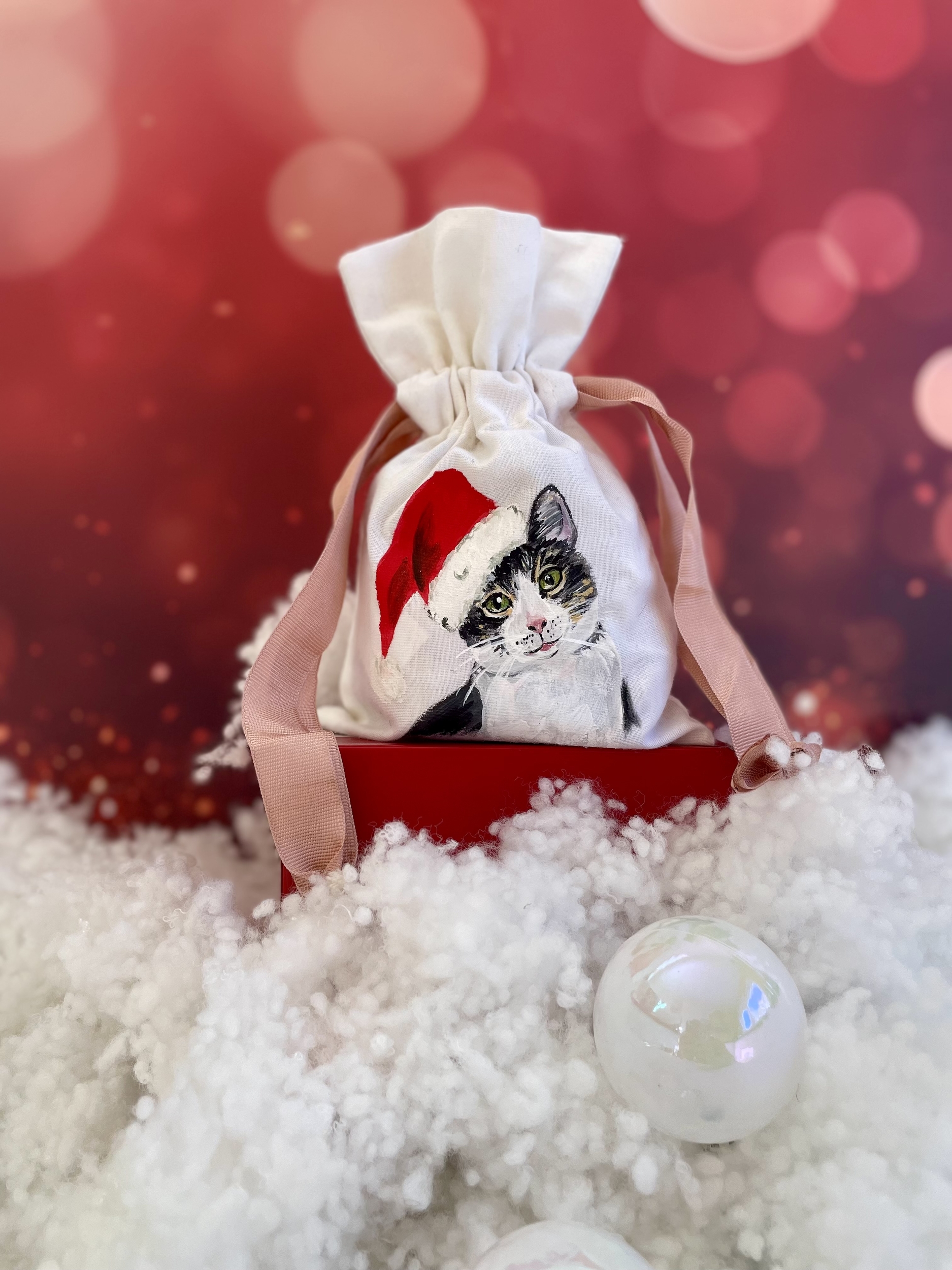 Pochon en coton blanc et ruban de satin rose avec un chat portant un bonnet de Père Noël peint à la main par Elles et No.